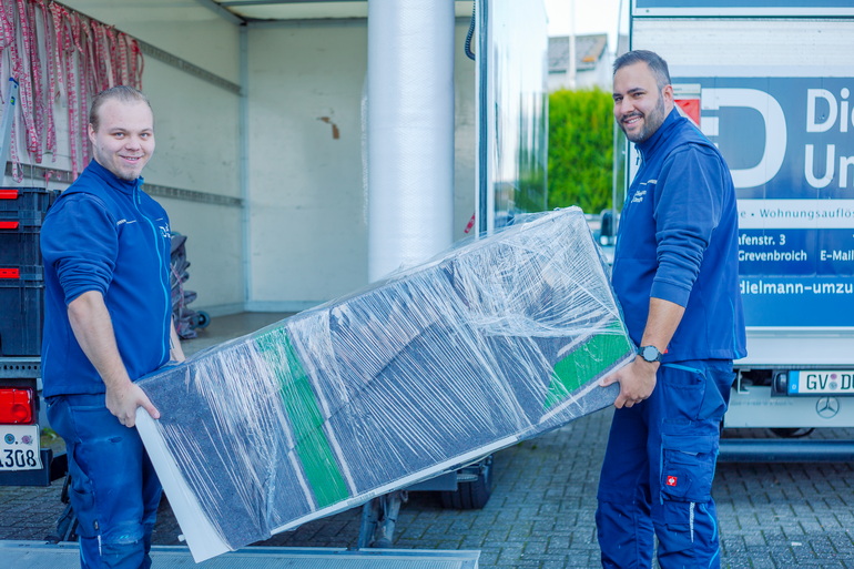 Das Bild zeigt zwei Mitarbeiter der Firma Dielmann-Umzüge beim Verladen eines Kühlschranks in Rommerskirchen